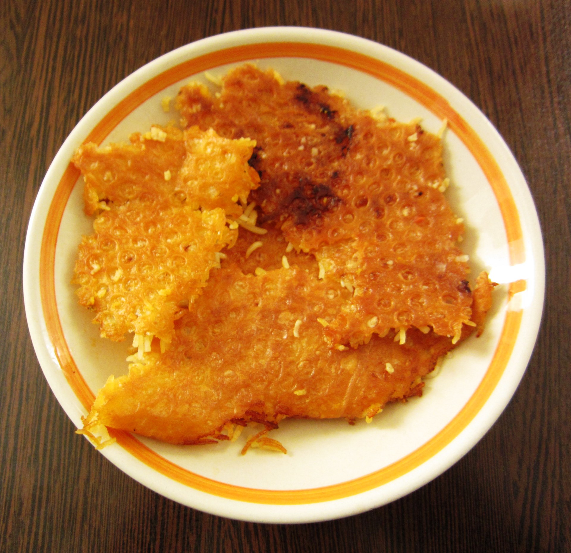 Crisp pieces of bread tahdig with rice still attached, on a plate.