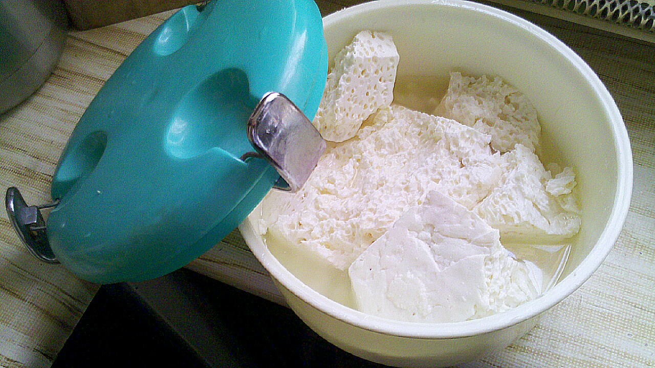 A bowl of soft white Persian cheese curd draining, seen whole on a table