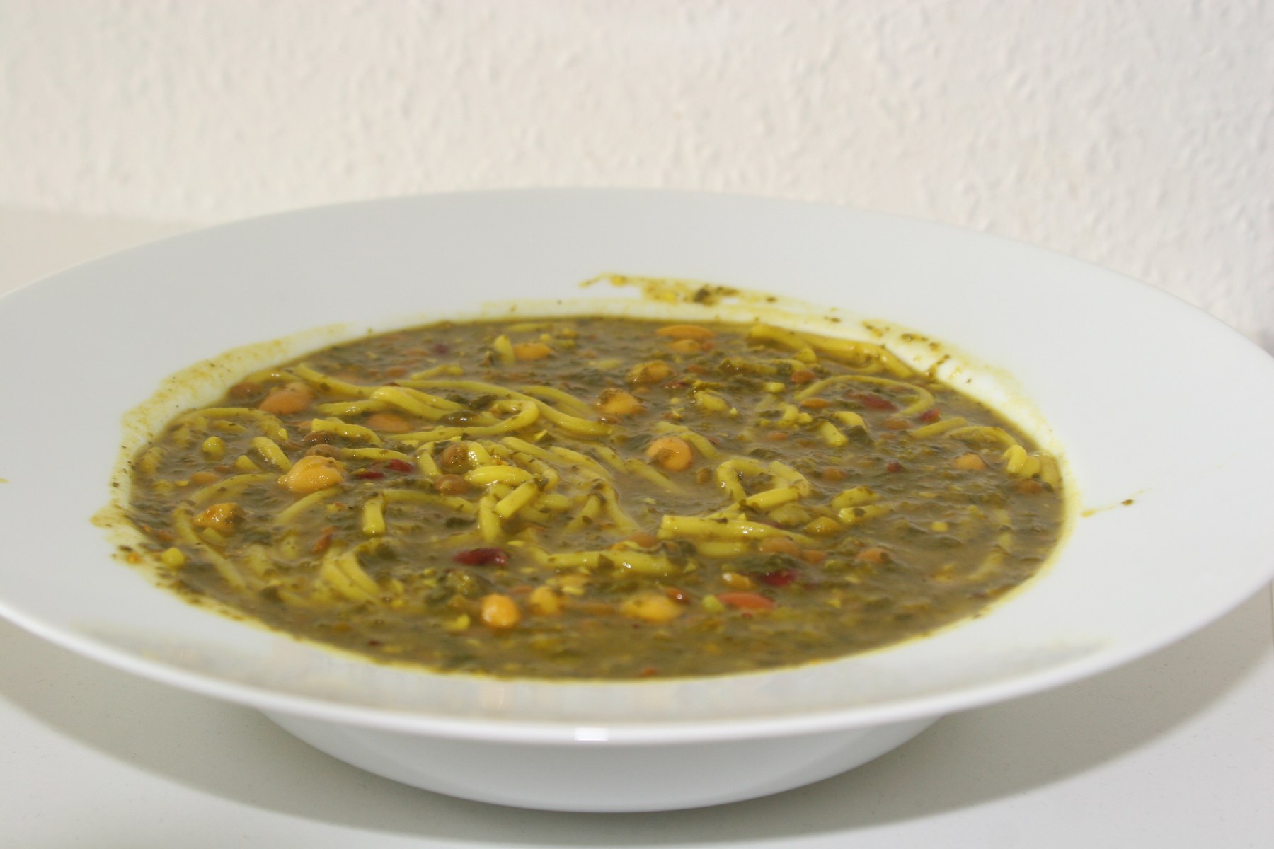 Ash reshteh — Persian herb, bean and noodle soup topped with kashk.