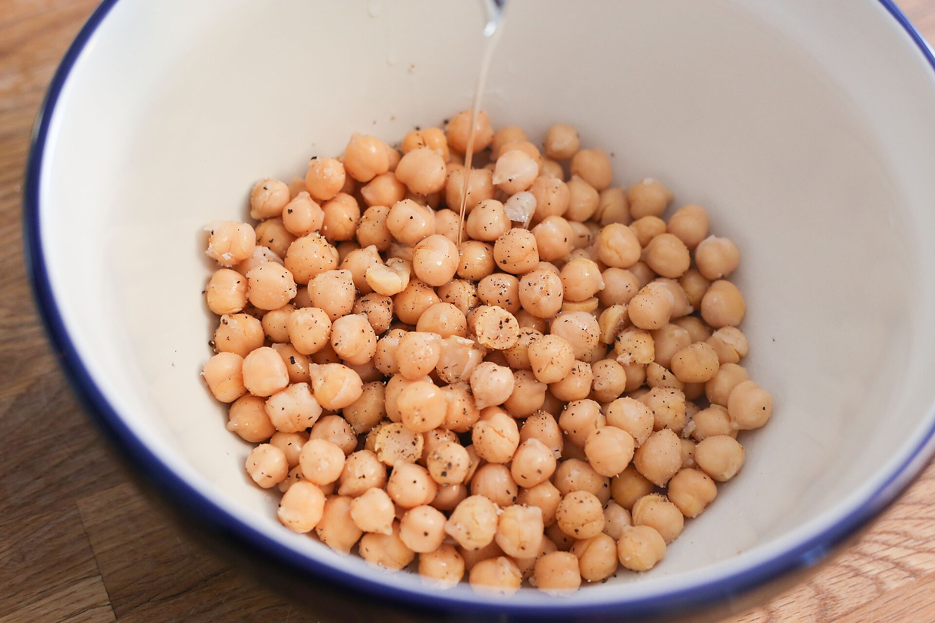 Pale tan whole dried chickpeas rinsed and gathered in a blue-rimmed enamel mixing bowl