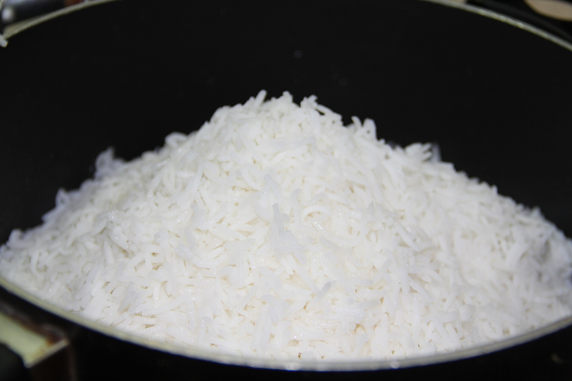 Parboiled rice piled in a pyramid inside a black pot.